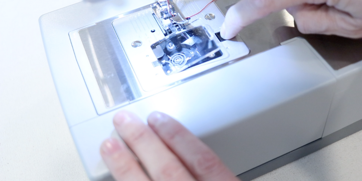 Opening the clear door on the bobbin cartridge. How to thread a sewing machine for beginners